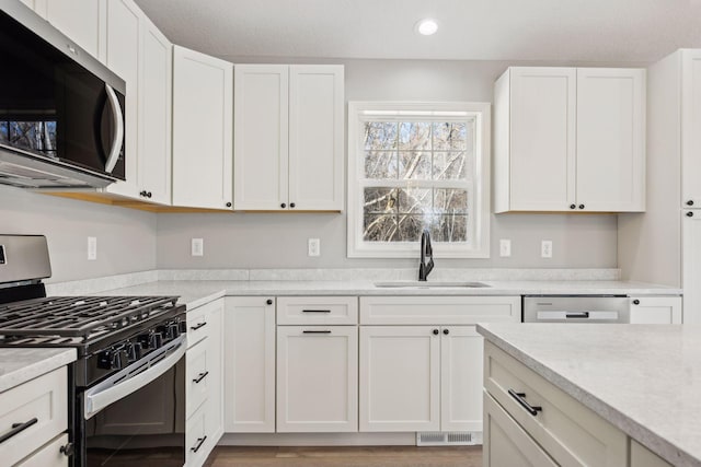 kitchen featuring appliances with stainless steel finishes, white cabinetry, and sink