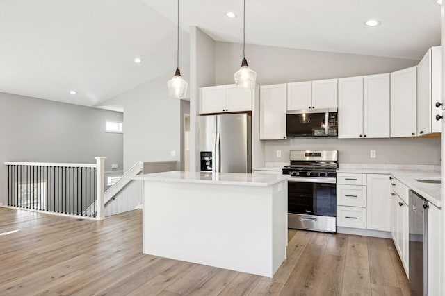 kitchen with white cabinets, appliances with stainless steel finishes, a center island, and hanging light fixtures