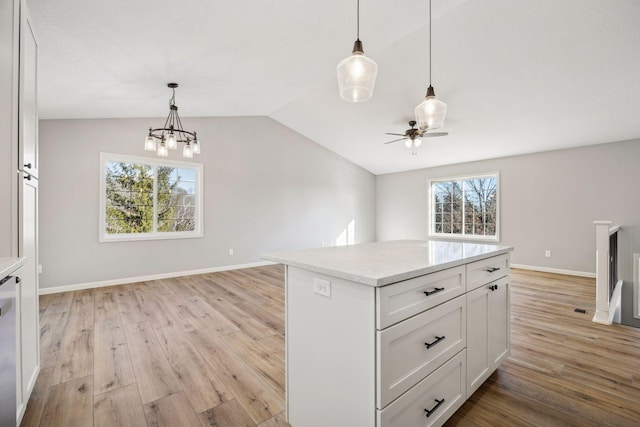 kitchen with vaulted ceiling, white cabinets, light hardwood / wood-style floors, and decorative light fixtures