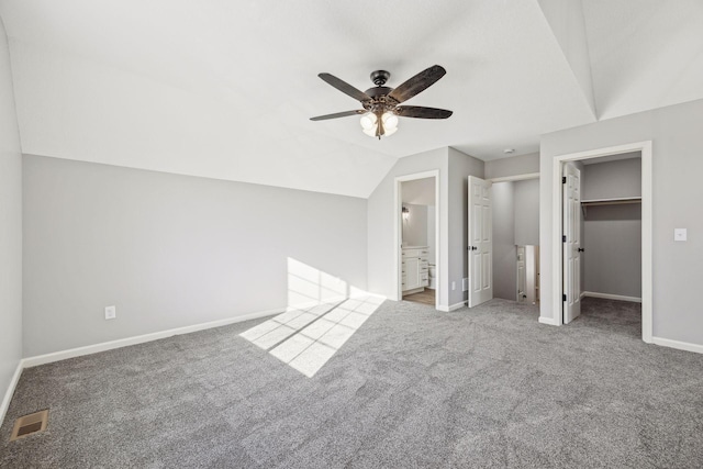 unfurnished bedroom with ensuite bath, carpet flooring, ceiling fan, a spacious closet, and a closet