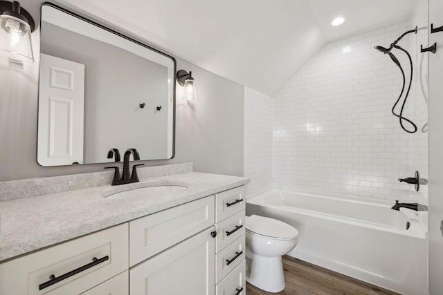 full bathroom with vanity, lofted ceiling, tiled shower / bath, hardwood / wood-style flooring, and toilet