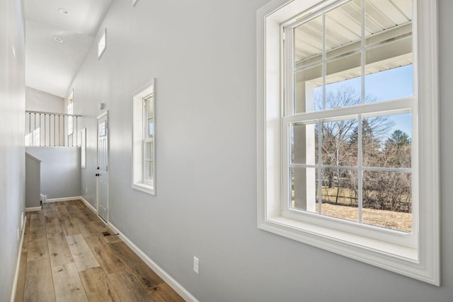 hall featuring light wood-type flooring and vaulted ceiling