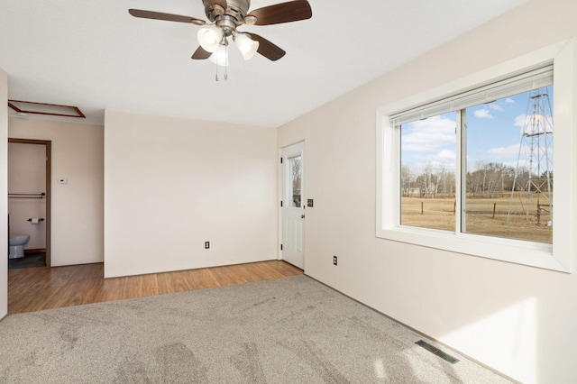 spare room with visible vents, carpet floors, wood finished floors, and a ceiling fan