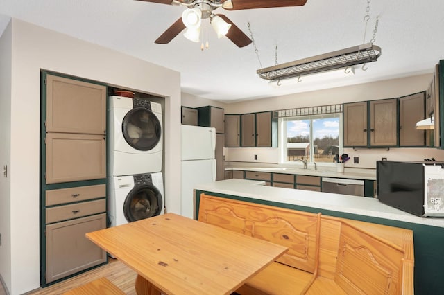 kitchen with light countertops, freestanding refrigerator, stacked washer / drying machine, a ceiling fan, and stainless steel dishwasher