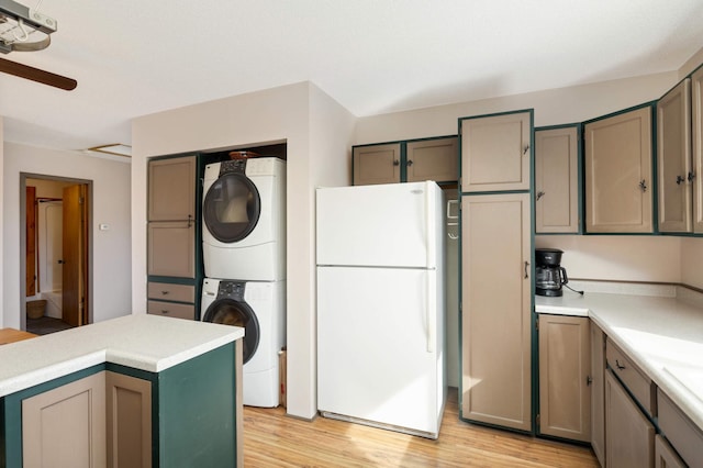 kitchen featuring light wood-type flooring, gray cabinets, freestanding refrigerator, stacked washer / dryer, and light countertops