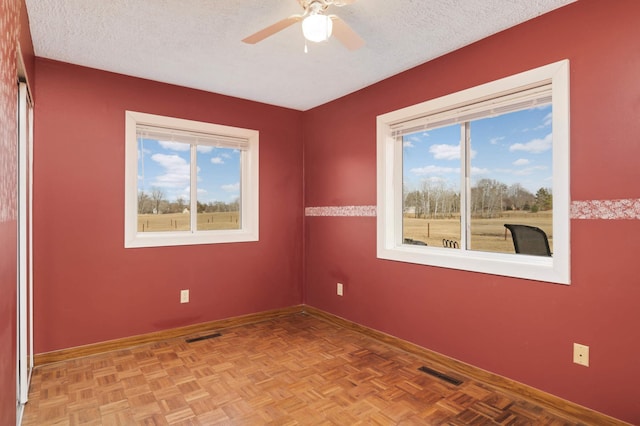 empty room with baseboards, visible vents, a textured ceiling, and a ceiling fan