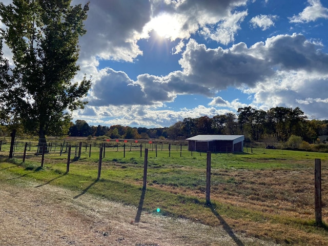 view of yard featuring a rural view, an outdoor structure, and fence