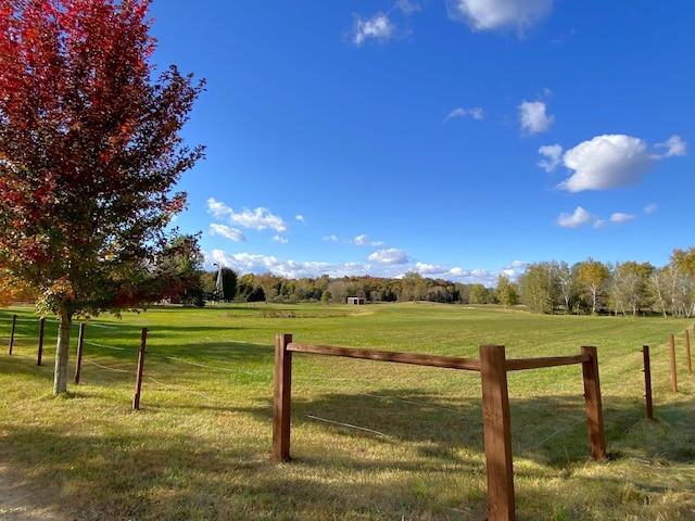 view of gate with a rural view, a yard, and fence