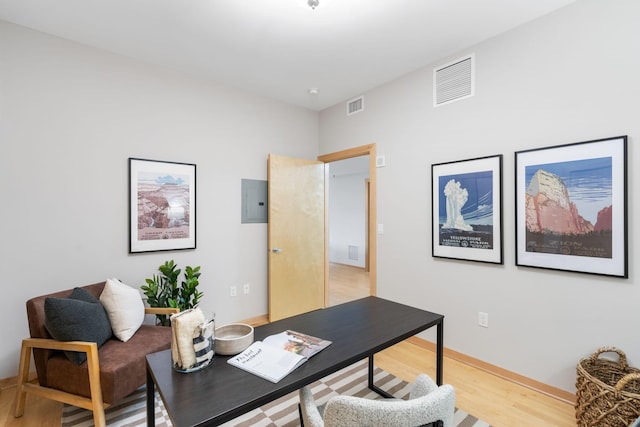 home office with electric panel and light hardwood / wood-style floors