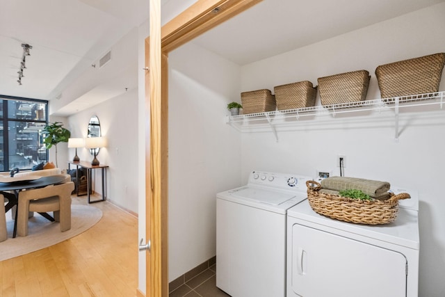 laundry room featuring separate washer and dryer, track lighting, and hardwood / wood-style flooring