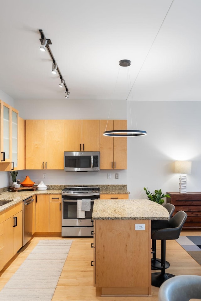 kitchen with a center island, a breakfast bar area, light brown cabinetry, appliances with stainless steel finishes, and light wood-type flooring