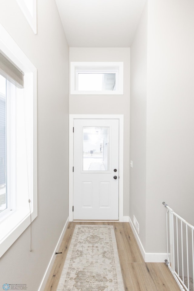 doorway to outside featuring a wealth of natural light and light hardwood / wood-style floors