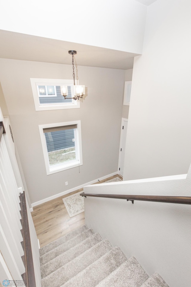 stairs featuring hardwood / wood-style floors and an inviting chandelier