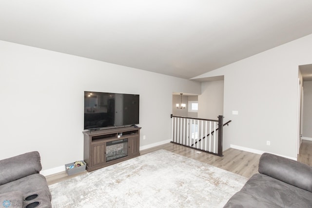 living room featuring light hardwood / wood-style floors, lofted ceiling, and a notable chandelier