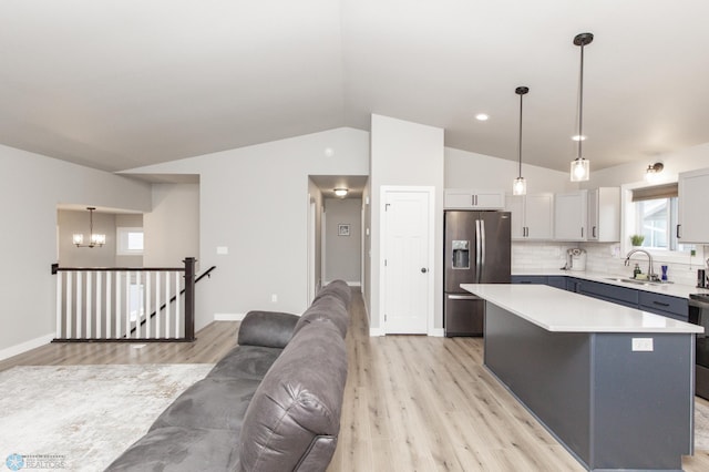 kitchen featuring pendant lighting, sink, decorative backsplash, stainless steel fridge, and a kitchen island