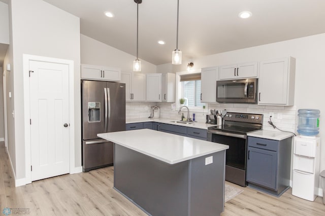 kitchen featuring a center island, hanging light fixtures, sink, vaulted ceiling, and appliances with stainless steel finishes