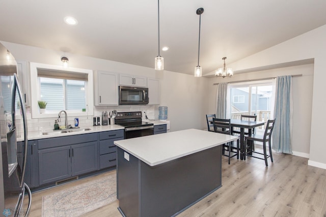 kitchen featuring sink, a center island, stainless steel appliances, decorative light fixtures, and vaulted ceiling