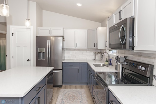 kitchen with decorative backsplash, appliances with stainless steel finishes, vaulted ceiling, pendant lighting, and white cabinetry