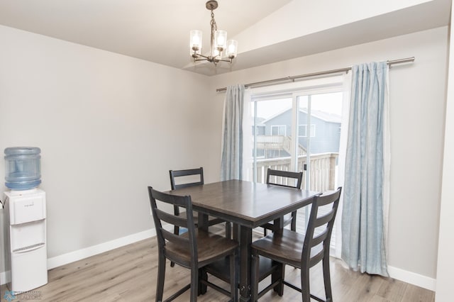 dining room with light hardwood / wood-style floors, vaulted ceiling, and a notable chandelier