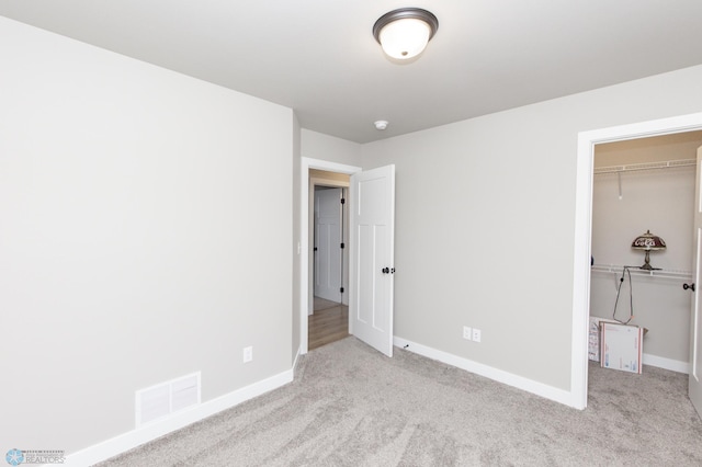 unfurnished bedroom featuring light colored carpet, a spacious closet, and a closet