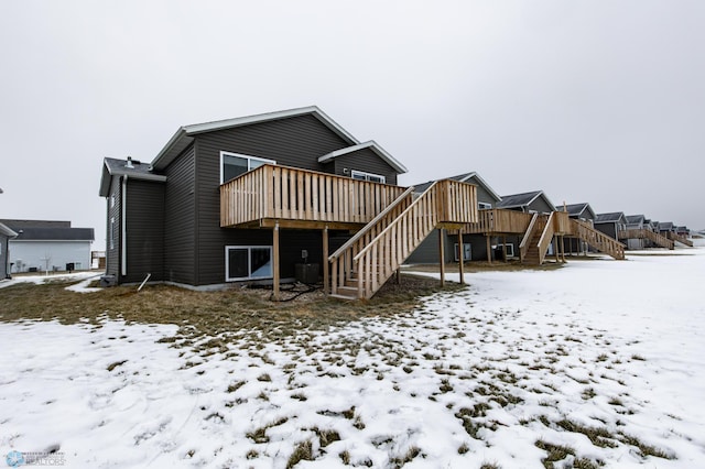 snow covered back of property featuring a wooden deck and central AC