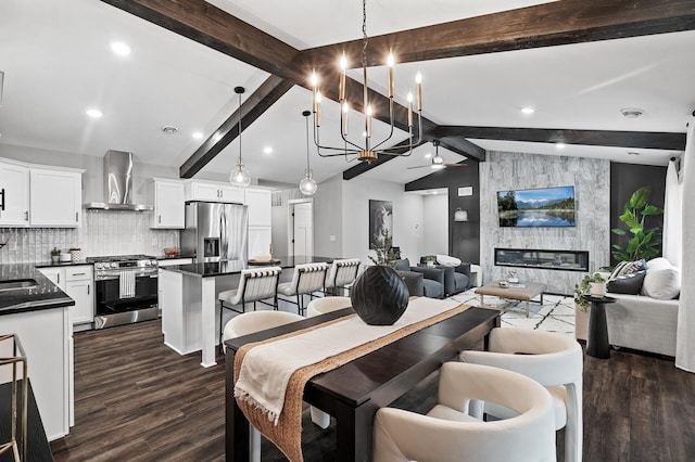 dining area with ceiling fan with notable chandelier, sink, a fireplace, vaulted ceiling with beams, and dark hardwood / wood-style floors