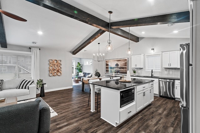 kitchen with a kitchen bar, appliances with stainless steel finishes, backsplash, white cabinets, and a center island