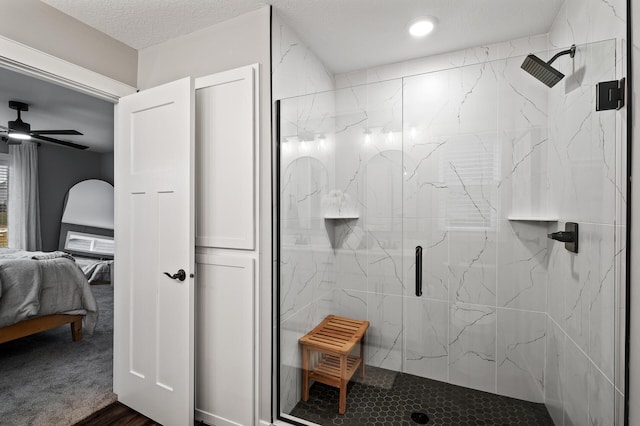 bathroom with ceiling fan, an enclosed shower, wood-type flooring, and a textured ceiling