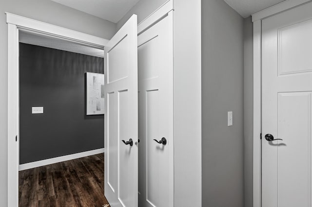 hallway with dark hardwood / wood-style floors and a textured ceiling