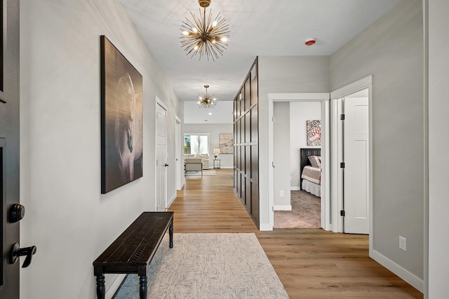 hall featuring light hardwood / wood-style flooring and a notable chandelier