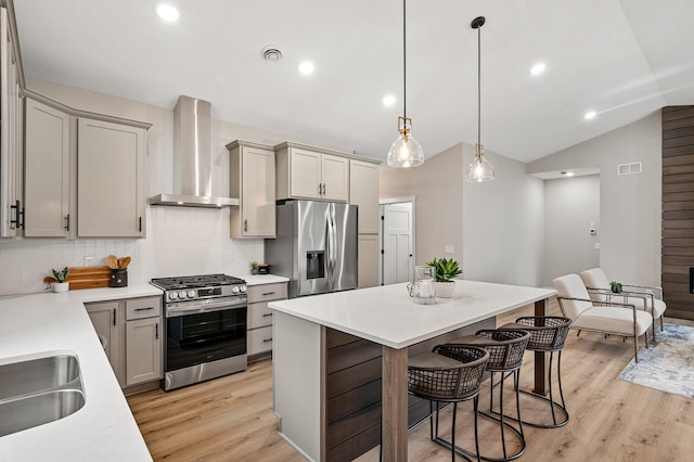 kitchen featuring wall chimney range hood, decorative light fixtures, gray cabinets, decorative backsplash, and appliances with stainless steel finishes