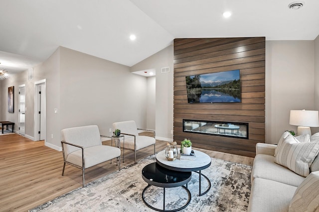 living room with a large fireplace, light hardwood / wood-style floors, and lofted ceiling