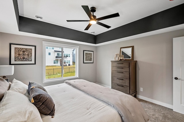 bedroom featuring a tray ceiling, ceiling fan, and light carpet