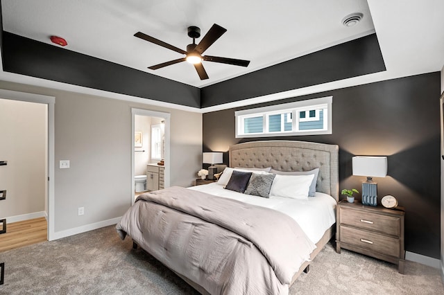 bedroom with ceiling fan, ensuite bathroom, and light colored carpet