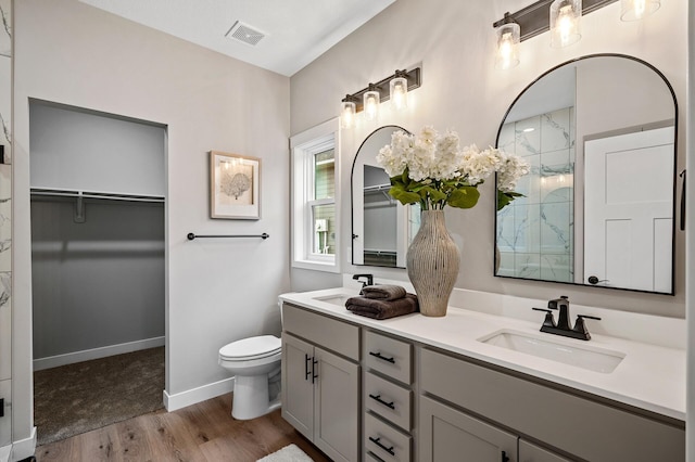 bathroom with hardwood / wood-style floors, vanity, toilet, and walk in shower