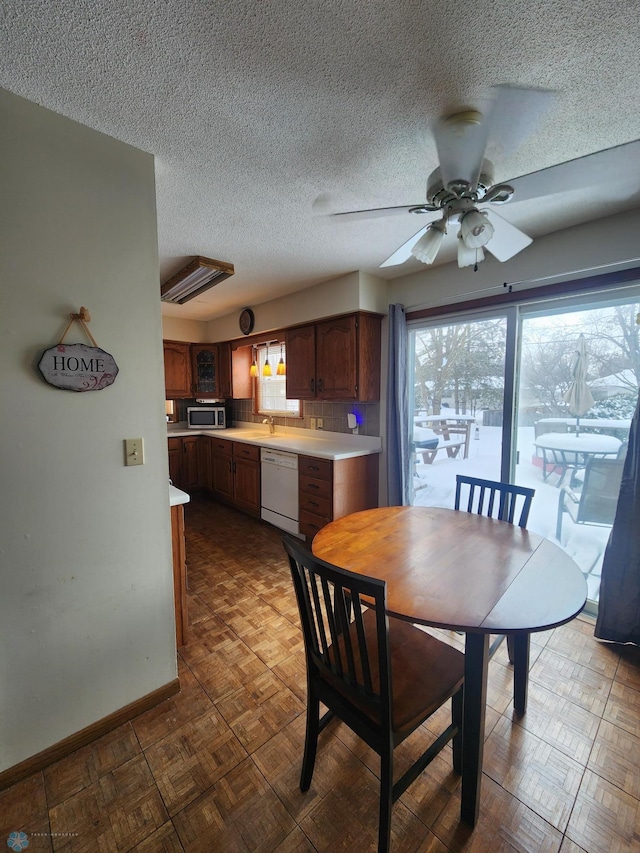 dining room featuring ceiling fan, parquet flooring, a textured ceiling, and a wealth of natural light