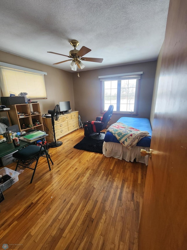 bedroom with ceiling fan, hardwood / wood-style floors, and a textured ceiling