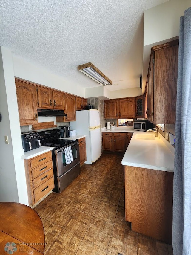 kitchen with stainless steel appliances, dark parquet floors, sink, and a textured ceiling