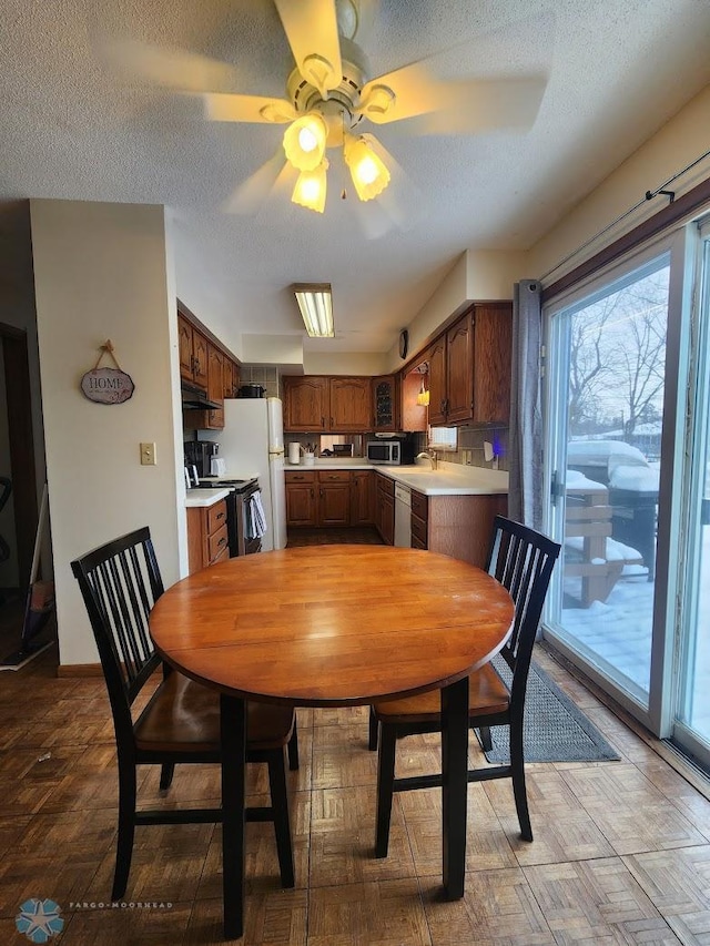 dining area featuring ceiling fan, sink, and a textured ceiling