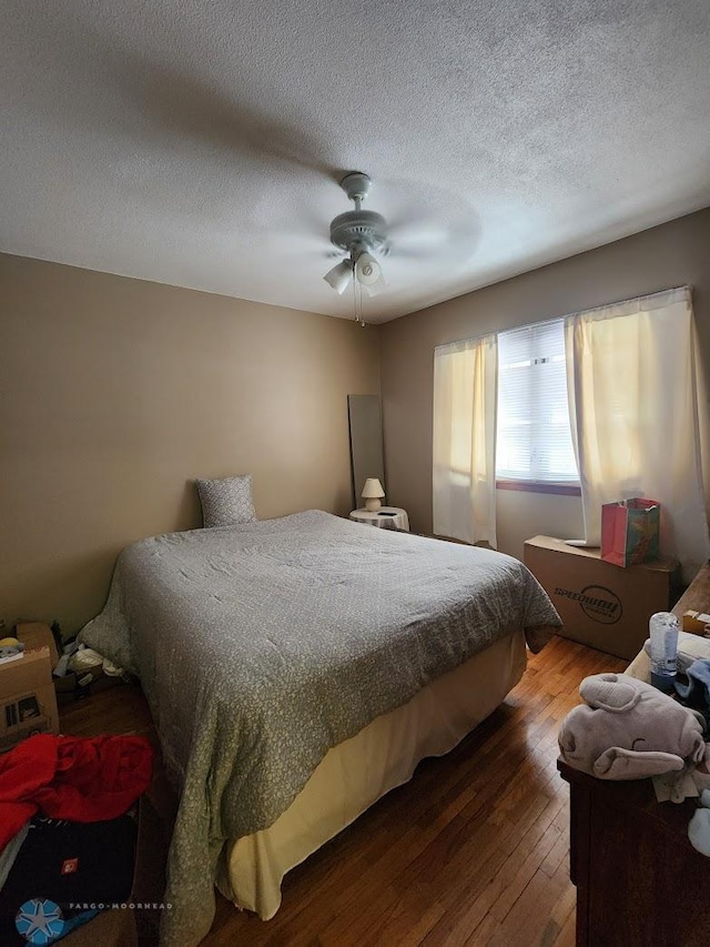 bedroom featuring wood-type flooring, ceiling fan, and a textured ceiling