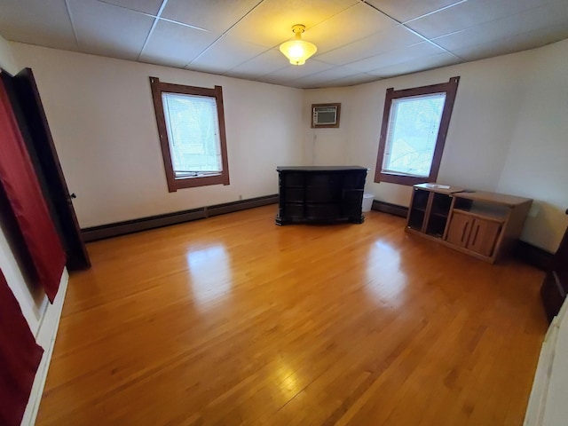 empty room with a wealth of natural light, a baseboard radiator, a wall mounted air conditioner, and hardwood / wood-style flooring