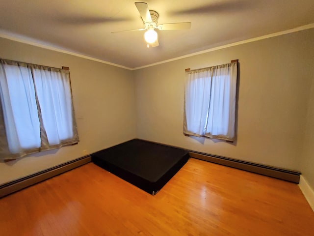 spare room with hardwood / wood-style flooring, ceiling fan, ornamental molding, and baseboard heating