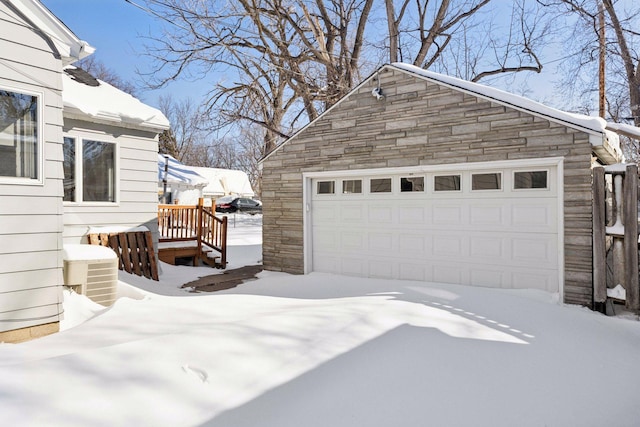 snow covered garage with a detached garage and central AC