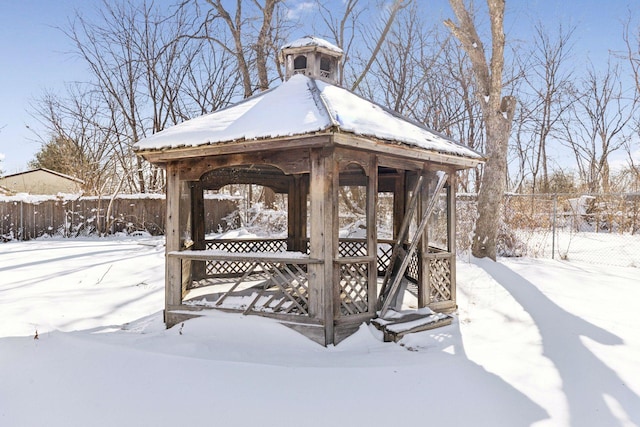 yard layered in snow featuring a gazebo and fence