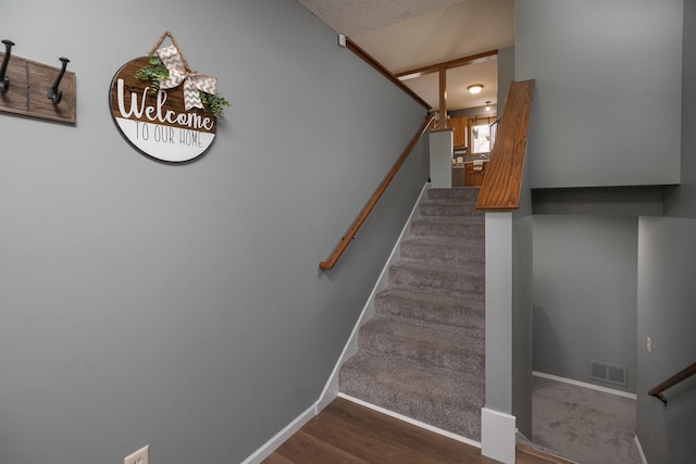 stairway featuring a textured ceiling and hardwood / wood-style flooring