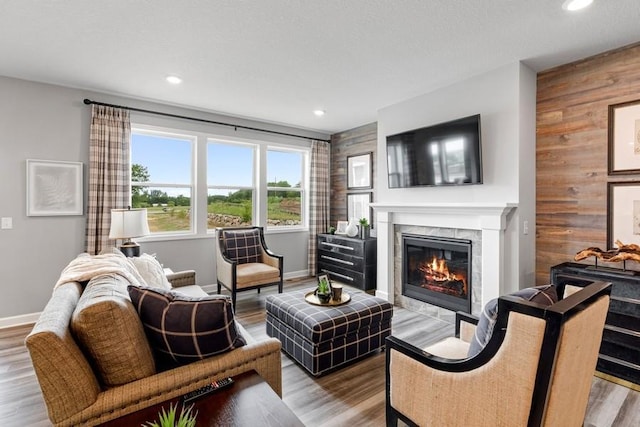 living room featuring hardwood / wood-style flooring, wood walls, and a fireplace