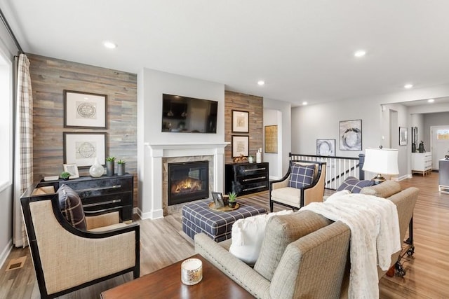 living room with wooden walls, light hardwood / wood-style floors, and a tile fireplace