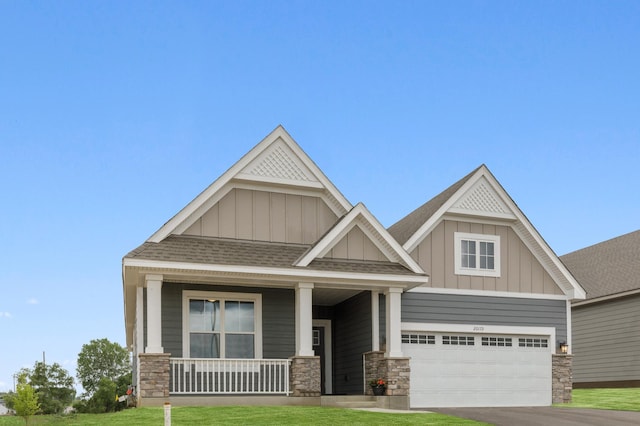 craftsman-style home featuring a front lawn, a porch, and a garage