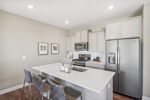 kitchen with a breakfast bar, white cabinets, stainless steel appliances, and a center island with sink