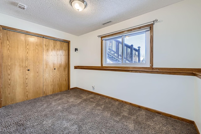 unfurnished bedroom featuring a textured ceiling, a closet, and carpet